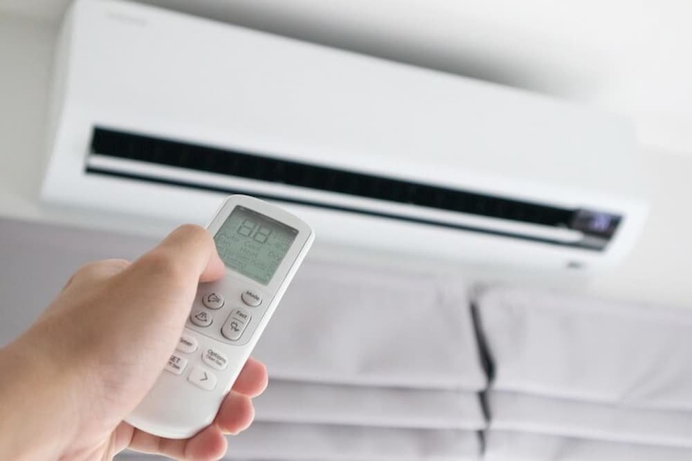 sistema split interior, una mano apunta a él con un mando a distancia